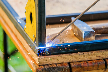 The tip of the electrode of electric arc welding melts the metal. Selective focus. Flash, sparks and smoke during the burning of metal.