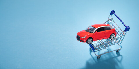 Toy red car with a shopping cart on the blue background.