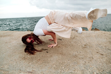 Hip-hop dancer breakdancing outdoors with the sea in the background.
