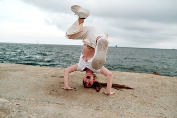 Young dancer enjoying dancing freestyle outdoors with the sea on background.