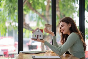 Women support model houses with two hands and give the house over to customers or homebuyers. Rent...