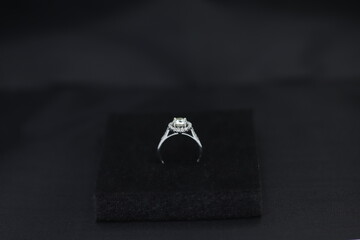 Fine jewelry as diamond ring with diamond with black satin fabric background. Jewelry shop concept