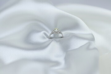 Fine jewelry as diamond ring with diamond with white satin fabric background. Jewelry shop concept