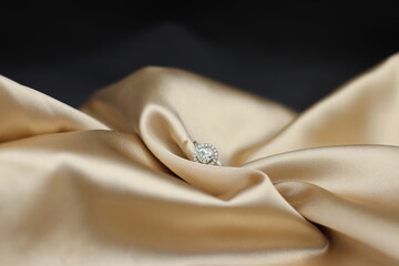 Fine jewelry as diamond ring with diamond with golden satin fabric background. Jewelry shop concept