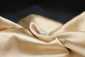 Fine jewelry as diamond ring with diamond with golden satin fabric background. Jewelry shop concept