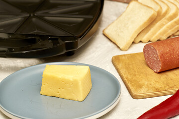 sandwich maker cheese sausage and bread on the table