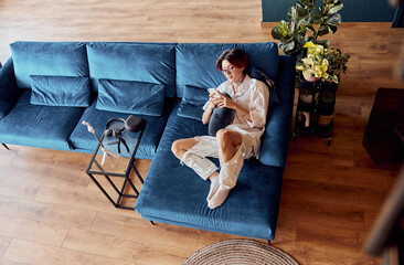 Asian man lying on the sofa while chatting on mobile phone