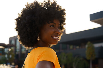 Portrait of young black woman with afro hairstyle smiling in urban background