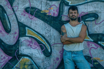grunge young man with crossed arms on graffiti wall