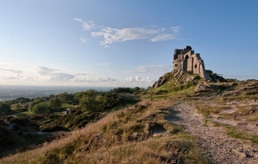 Fototapeta na wymiar Mow Cop Castle, Cheshire / Staffordshire, England in sunlight with blue sky, clouds and distant landscape; landscape format.