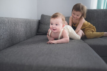 Sibling children play on sofa in living room together