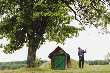 Man working in the garden with rake in a sunny day. Farmer working in the backyard