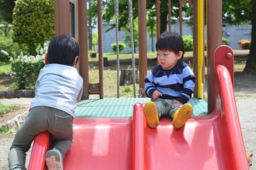 Fototapeta na wymiar 公園の滑り台で遊ぶ兄弟　2歳と5歳