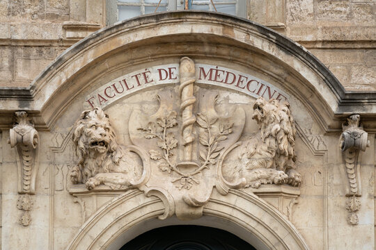 Montpellier, France, 07-08-2022 : View of beautiful ancient carved stone pediment with caduceus and lions above entrance of historic building of oldest faculty of medicine in the world still operating