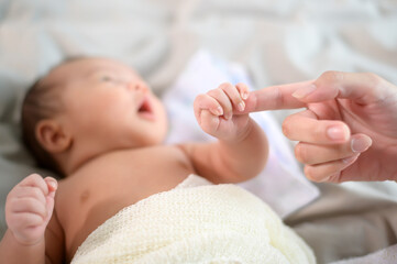 Close of hand holding new born baby's finger