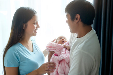 Smiling young mother and father with a new born baby, family and love concept