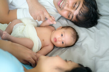 Smiling young mother and father with a new born baby, family and love concept