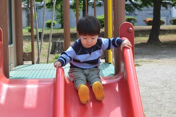 Fototapeta na wymiar 公園の滑り台で遊ぶ幼児　2歳