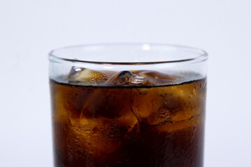 An isolated glass of black cola with ice is filled on white background