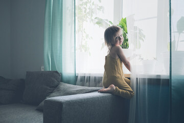 Cute girl child one gallops on couch in living room