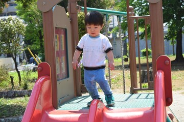 Fototapeta na wymiar 公園の滑り台で遊ぶ幼児　2歳