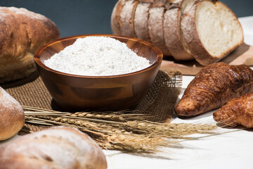 テーブルに並んだたくさんの種類のパンと小麦粉