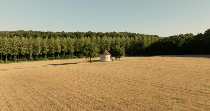 Aerial view of the chapel of the Liget next to wheat fields during sunset in France.