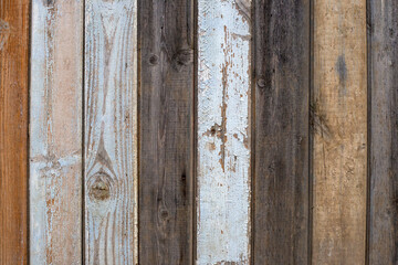 Wooden fence made of brown, gray and white painted boards. Wooden wall background. Old wood texture background