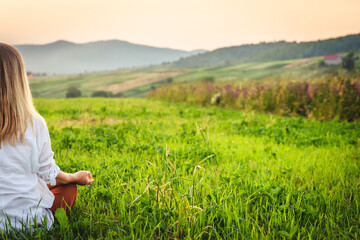 Woman doing yoga on the green grass at the mountain. Carpathians