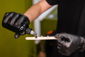 Male hands in gloves holding black ink. Tattoo artist preparing for work indoor. Small business and young professionals