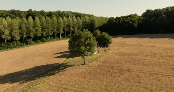 Aerial view of the chapel of the Liget next to wheat fields during sunset in France.