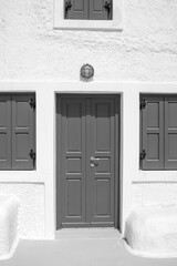 A typical residential building with blue shutters and a blue door in Santorini in black and white 