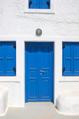 A typical residential building with blue shutters and a blue door in Santorini