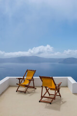 View of two empty sunbeds on the rooftop of a villa  and a spectacular view of the Aegean Sea  in Santorini Greece