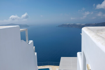 Obraz premium View of the steps of a typical whitewashed villa in Santorini and the Aegean Sea in the background