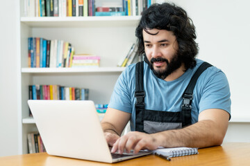 Handyman with beard ordering material online at computer