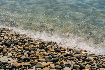 Bank of pebbles with the sea and beach in the background.