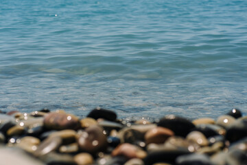 Bank of pebbles with the sea and beach in the background.