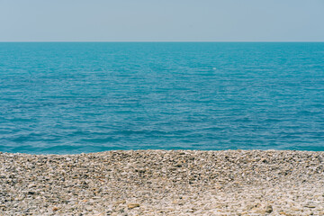 Obraz premium Bank of pebbles with the sea and beach in the background.