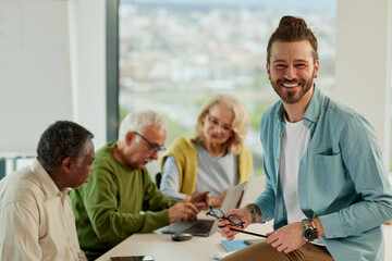 Multicultural group of senior students asking questions their tutor who showing them solution.