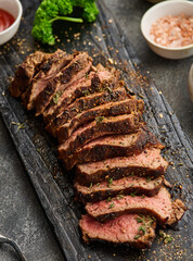 Grilled sliced beef steak on cutting board over grey table. Beef tenderloin steak. Filet Mignon recipe.