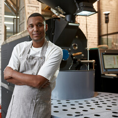 Black man near coffee roasting machine on factory
