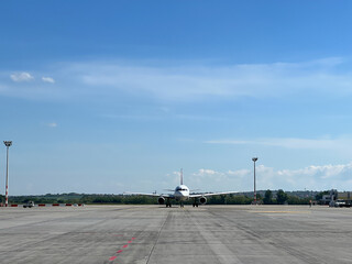 Plane stands on the runway at the airport against the blue sky