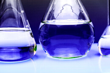 Three glass medical laboratory flasks with different multi-colored liquids and a glass bowl. The concept of medical and chemical experiments. close-up. copyspace.