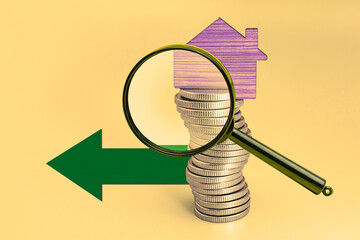 Purchase and sale of housing. Mortgage for the purchase of a house. Rental Property. A small wooden house stands on a stack of coins under a magnifying glass. Close-up. Copy space. Family savings.