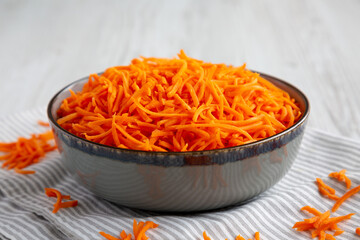 Raw Orange Carrot Shreds in a Bowl, low angle view. Close-up.