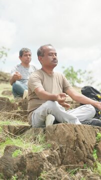 side view of Two Middle aged men with eyes closed doing meditation on top of hill during monring - concpet of mindfulness, self care and tranquility