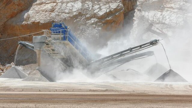 Stone crushing machine at open pit mining and processing plant for gravel stone. Piles of crushed stone and conveyor belts. Concepts of industry and building materials, sand and gravel