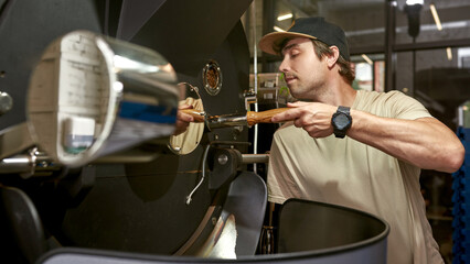 Worker operate coffee roasting machine on factory