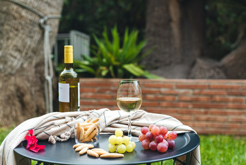 A glass of white wine with appetizers on the table.